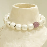 Silver cube necklace with ruby-pink CZ sphere displayed on white textured prop