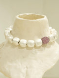 Silver cube necklace with ruby-pink CZ sphere displayed on white textured prop
