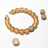 Gold cube necklace with matching dome ring laid flat on white