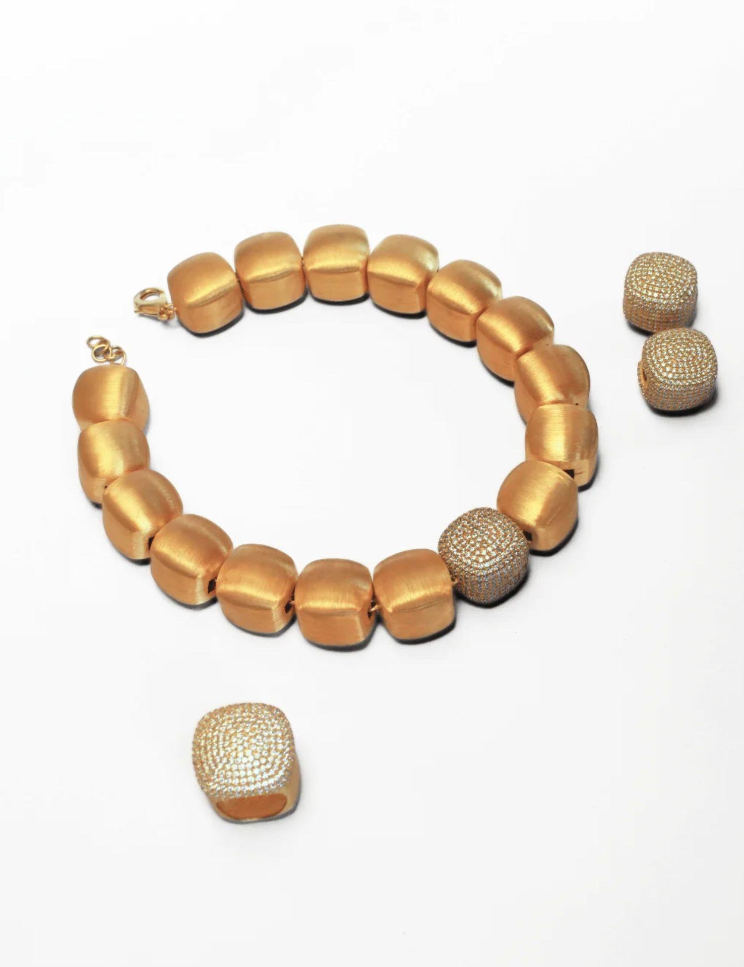 Gold cube necklace with matching dome ring laid flat on white