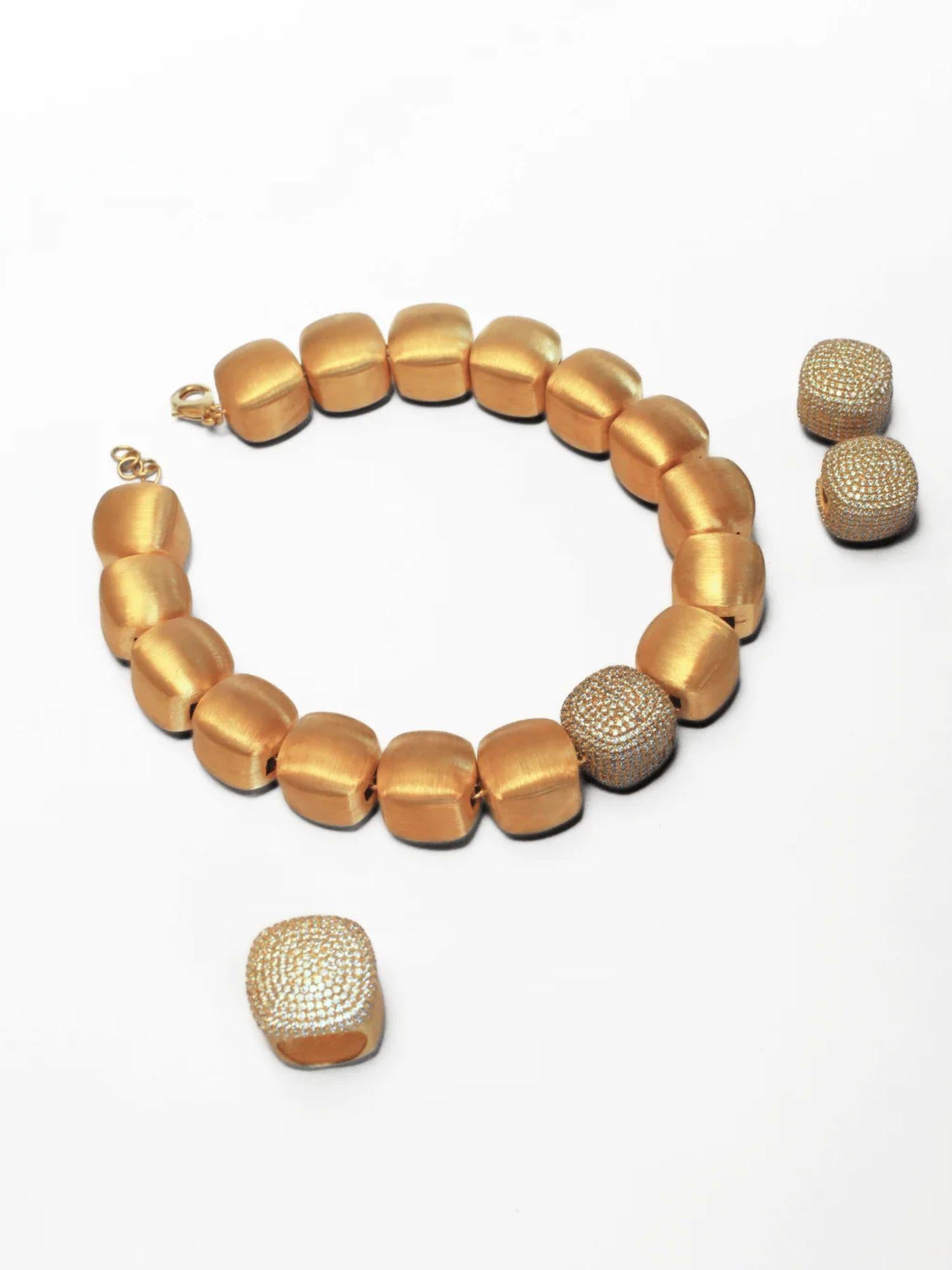 Gold cube necklace with matching dome ring laid flat on white
