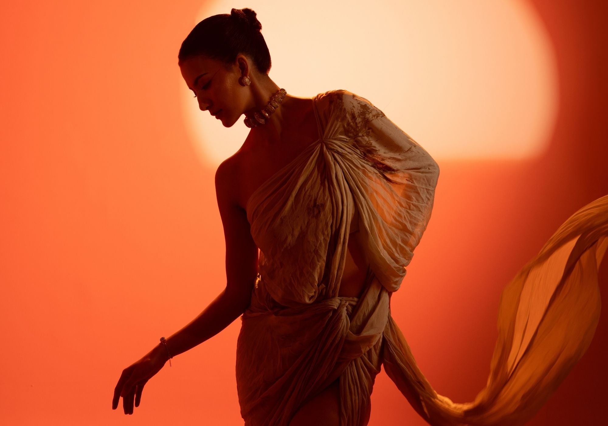 Model wearing MHARI jewellery in a flowing drape against a warm orange background, Ekant Collection editorial.