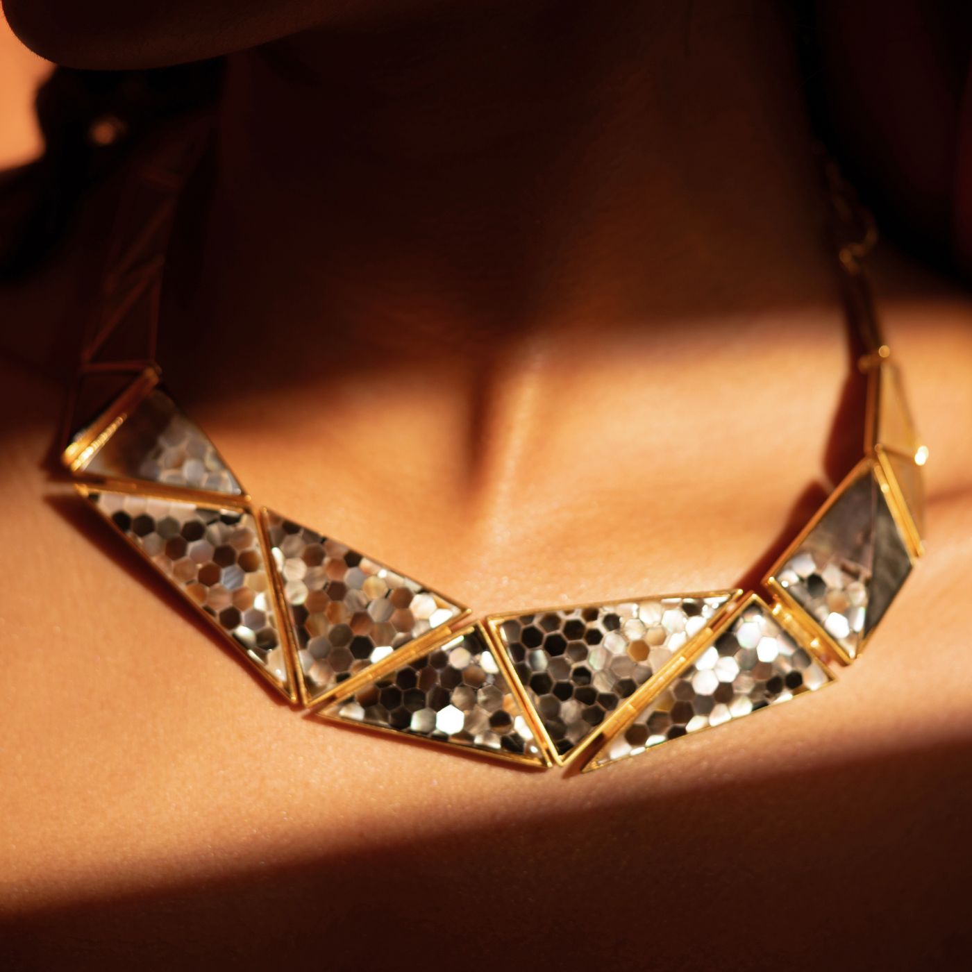 Model wearing geometric gold Mosaic necklace with mirror-finish hexagonal panels
