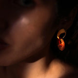 Close-up of gold and lab-grown amber hoop earring on model's ear in warm light