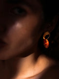 Close-up of gold and lab-grown amber hoop earring on model's ear in warm light