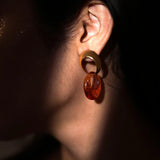 Side profile of model wearing gold amber double-hoop earring in low dark light