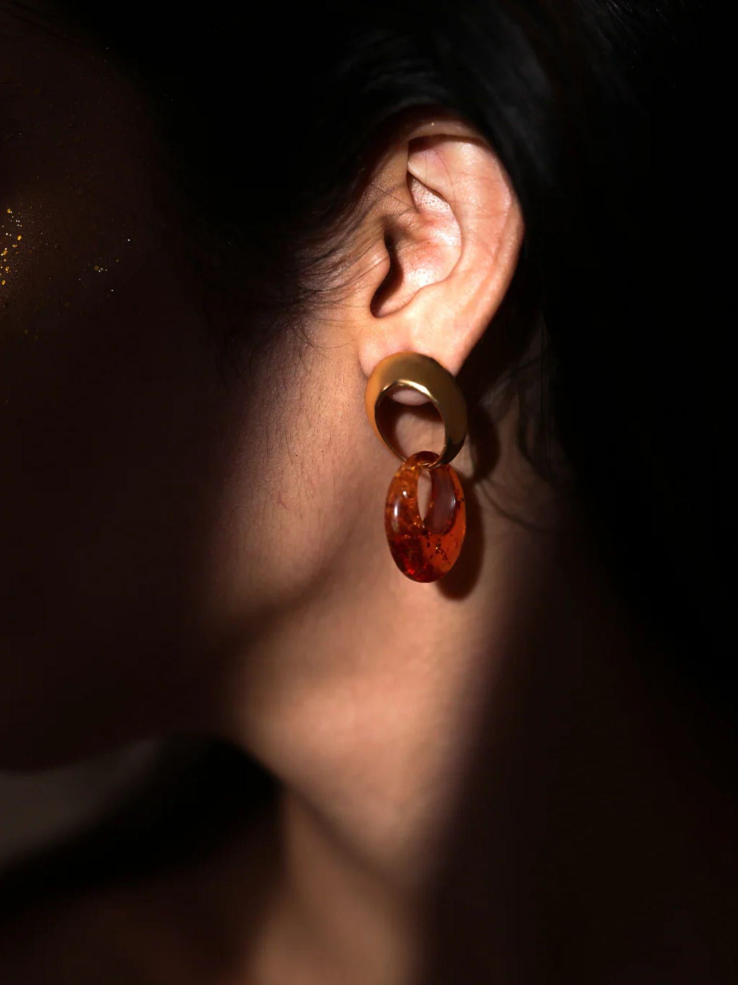 Side profile of model wearing gold amber double-hoop earring in low dark light