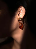 Side profile of model wearing gold amber double-hoop earring in low dark light