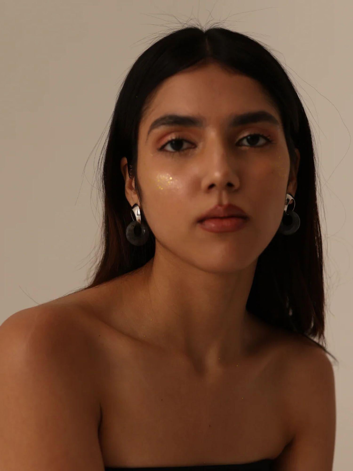 Model in neutral light wearing silver and amber mismatched hoop earrings, front portrait