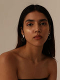 Model in neutral light wearing silver and amber mismatched hoop earrings, front portrait