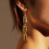 Model wearing long gold box link drop earrings, side profile in warm light