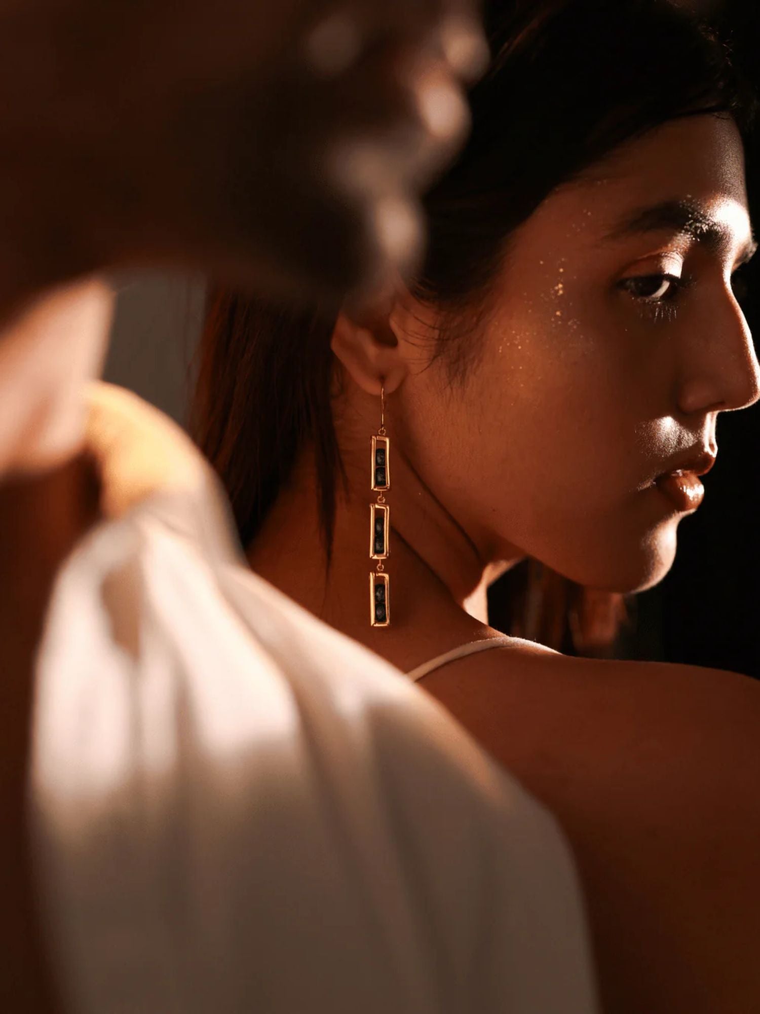 Model in editorial portrait wearing gold triple-drop box link earrings