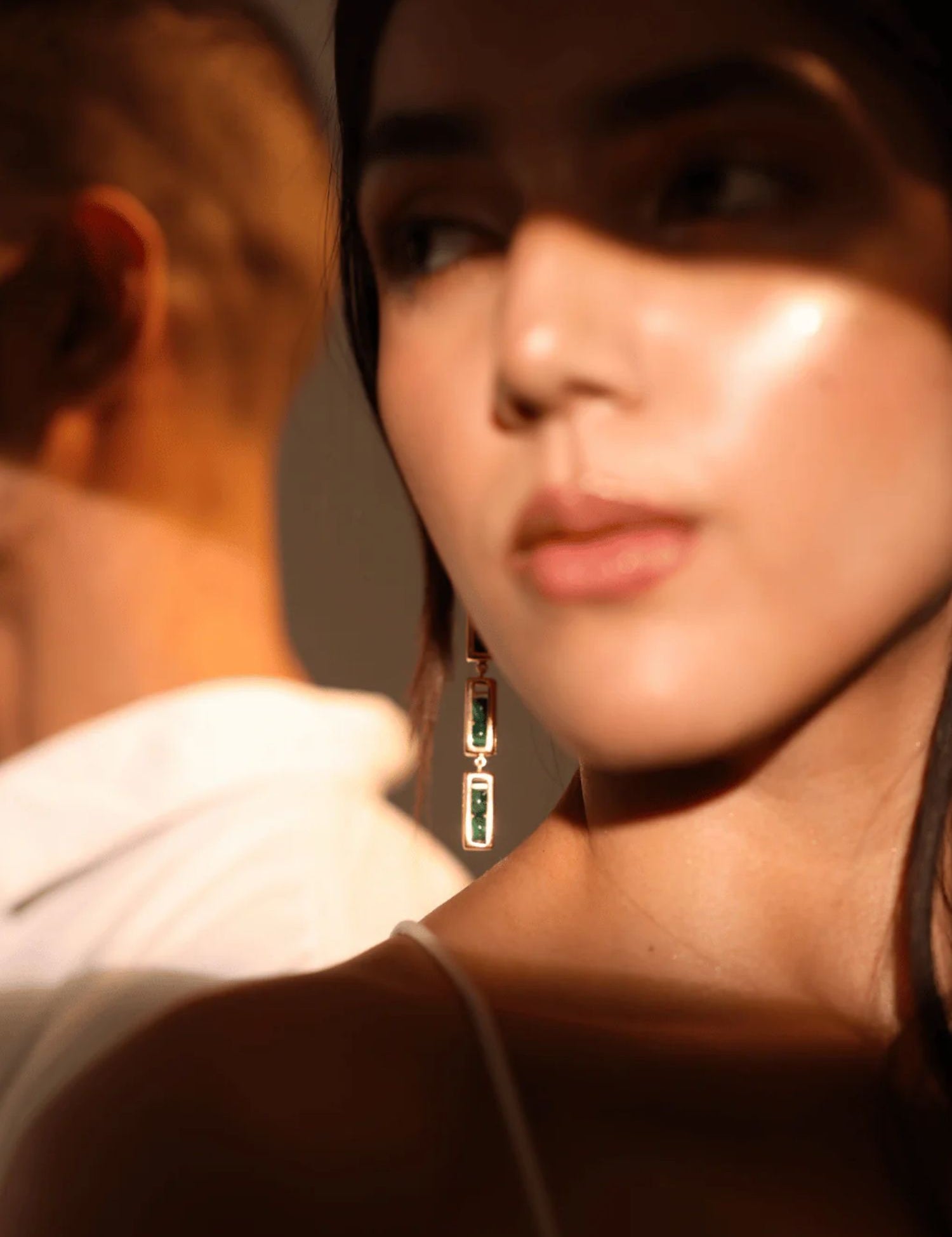 Model in warm light wearing gold interchangeable box link drop earrings, face forward