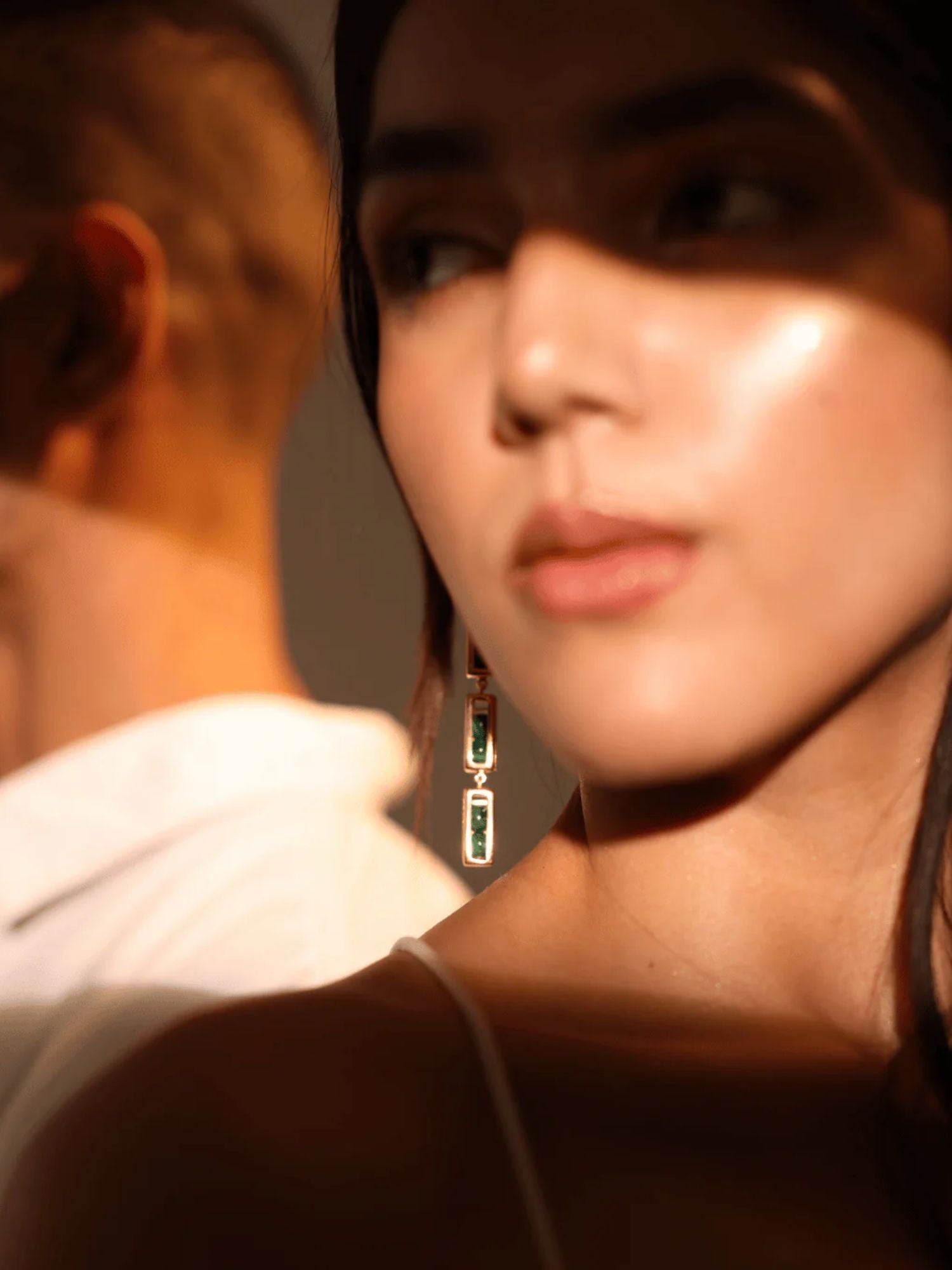 Model in warm light wearing gold interchangeable box link drop earrings, face forward