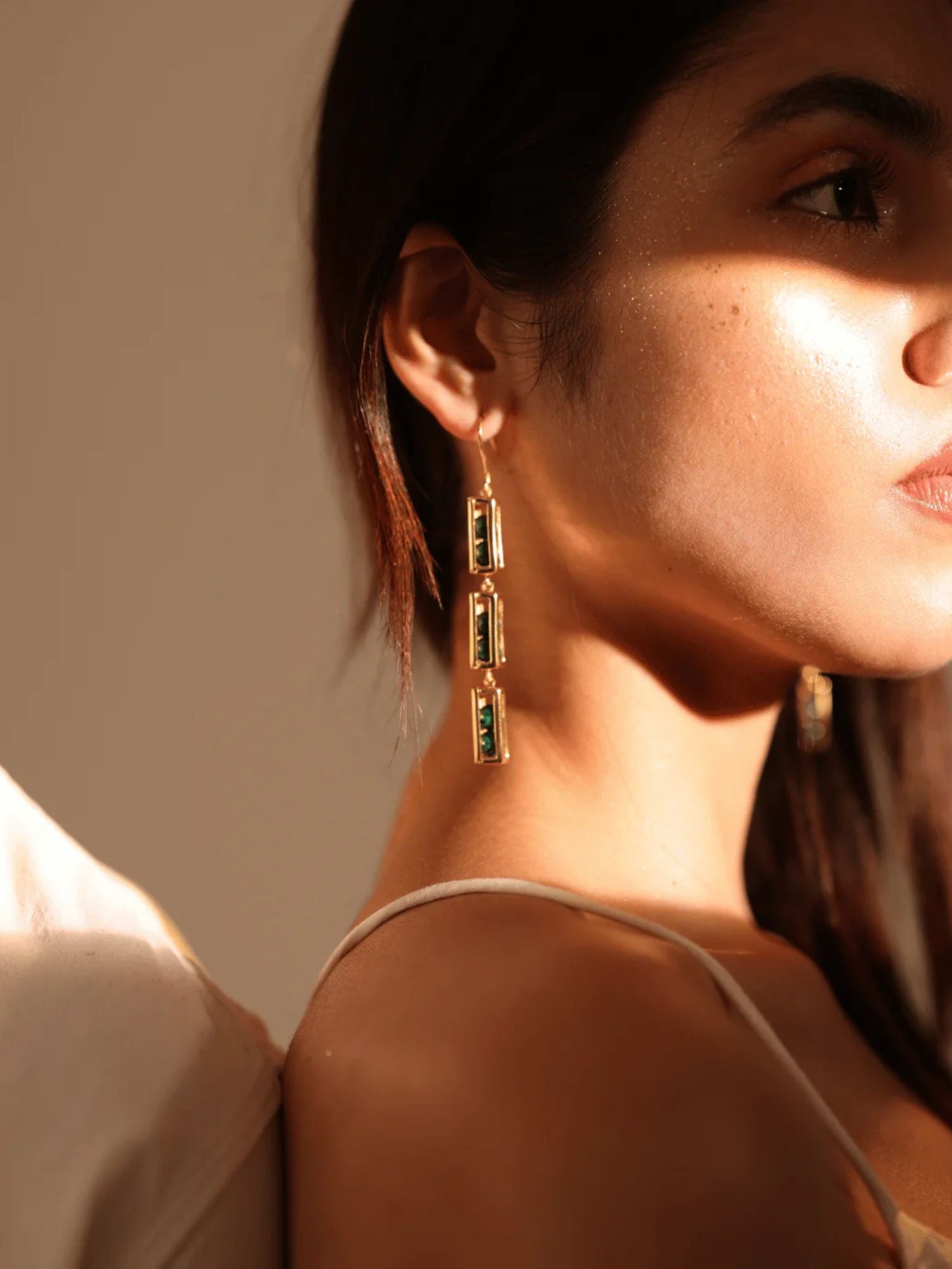 Side profile of model wearing long gold Fill Me In box link earrings in warm light
