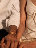 Couple resting together both wearing gold leather cord Fill Me In bracelets