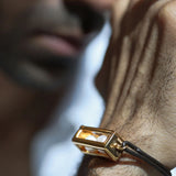 Close-up of male model wearing large gold box leather bracelet, chin in frame