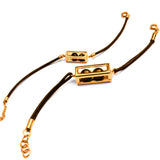 Flat lay of large gold interchangeable box on leather cord bracelet on white