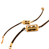 Flat lay of gold interchangeable box on leather cord bracelet on white