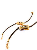 Flat lay of gold interchangeable box on leather cord bracelet on white