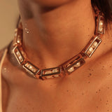 Model wearing large gold box link necklace with pearl beads, collarbone close-up