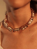 Model wearing large gold box link necklace with pearl beads, collarbone close-up