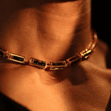 Model wearing gold box link choker necklace with agate beads, collarbone in warm light