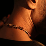 Male model wearing gold box link choker necklace, side profile in warm light