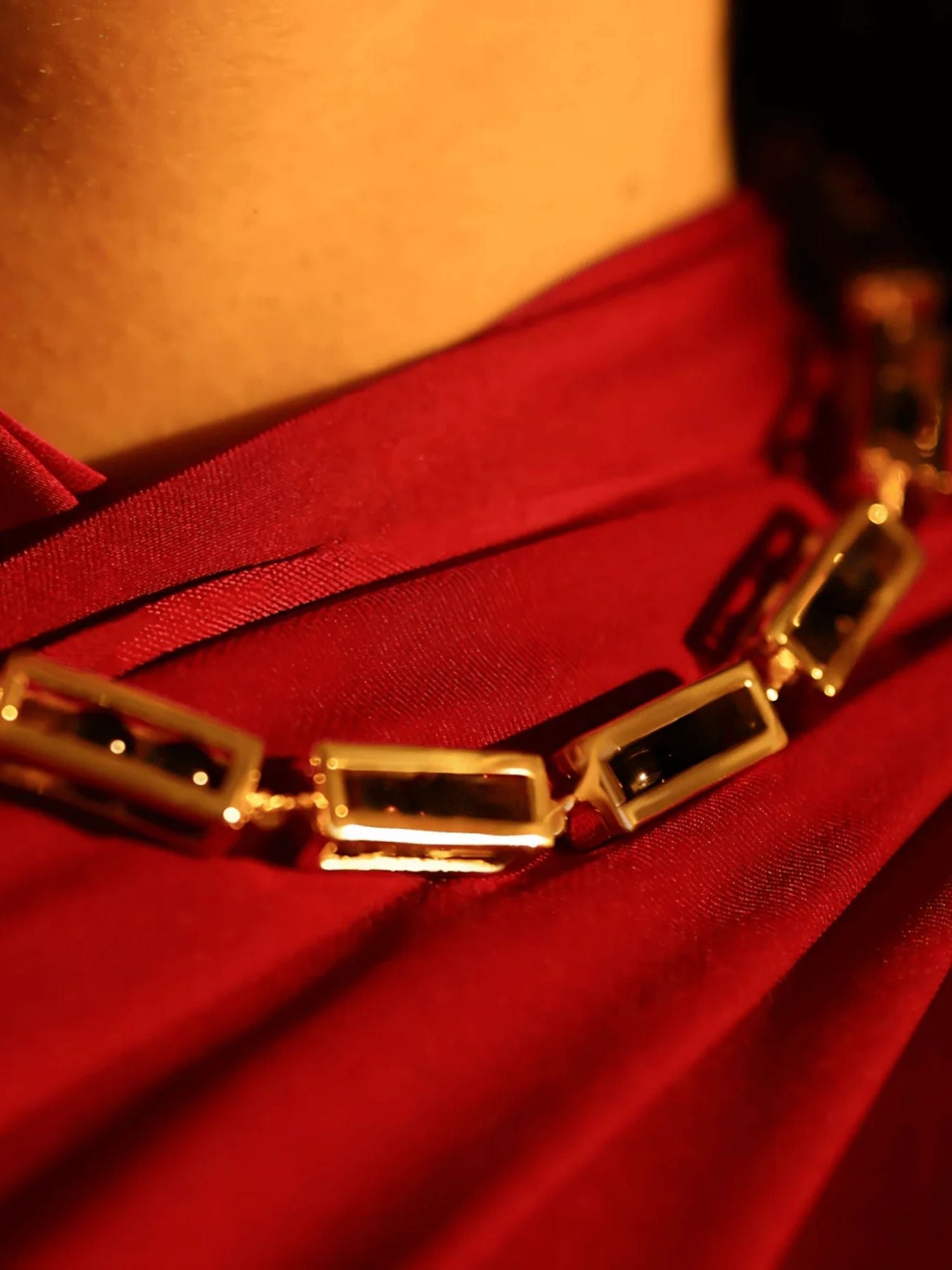 Gold box link necklace on model wearing red, close-up collarbone editorial shot