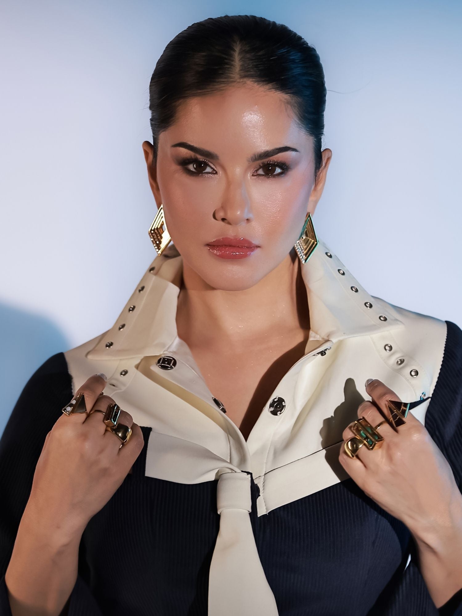 Model wearing large gold Fill Me In box ring stacked with other cocktail rings on both hands