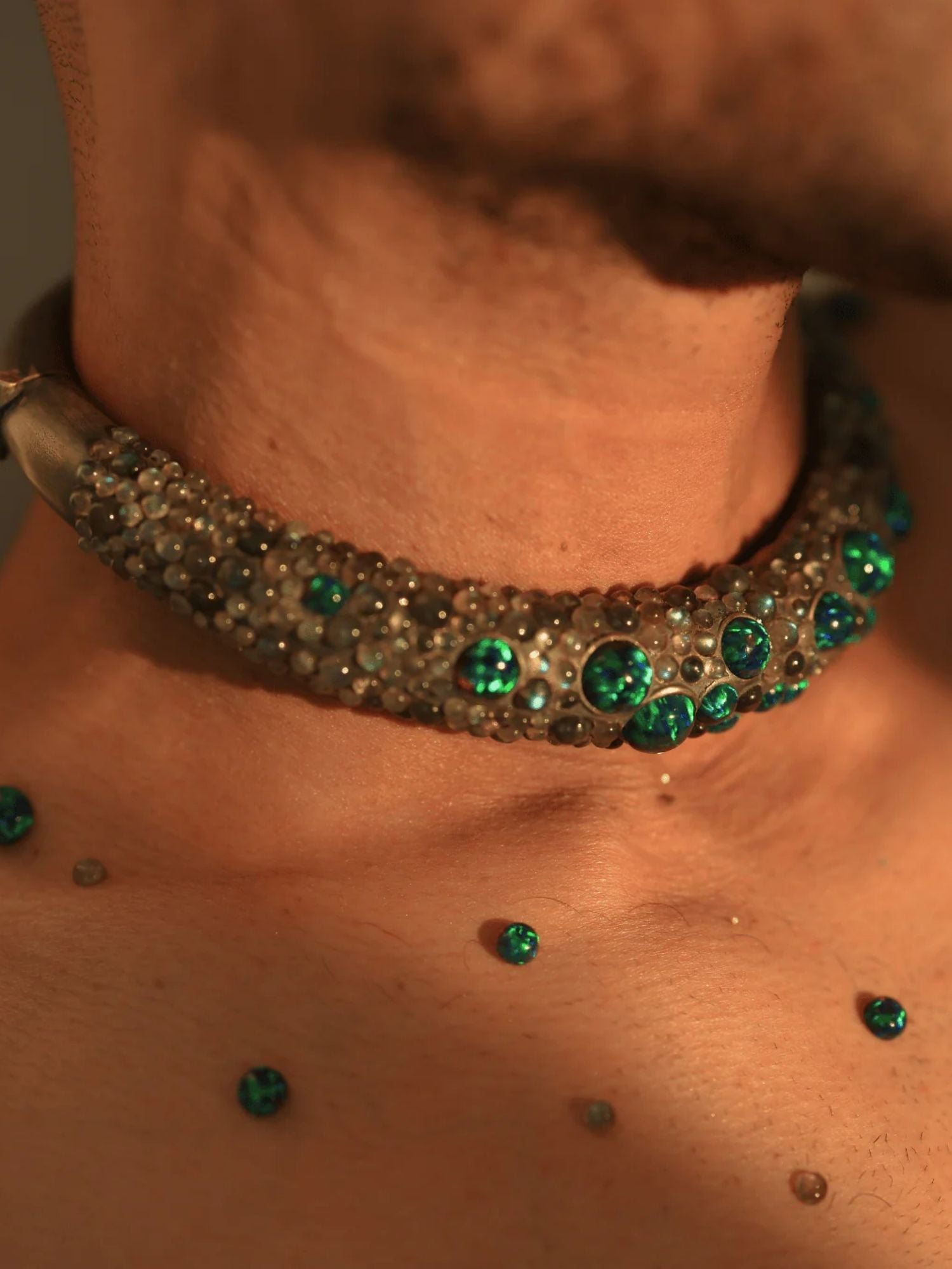 Green opal hasli necklace on male model's collarbone in warm close-up