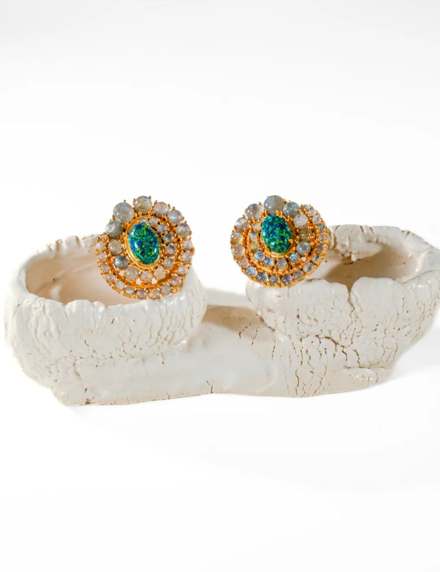 Green fire opal and labradorite spiral stud earrings on white sculptural prop