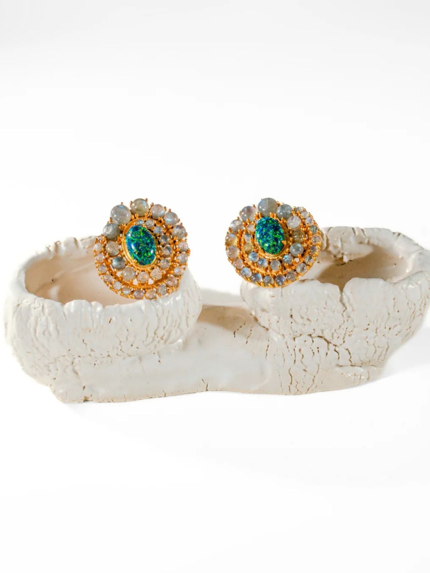 Green fire opal and labradorite spiral stud earrings on white sculptural prop