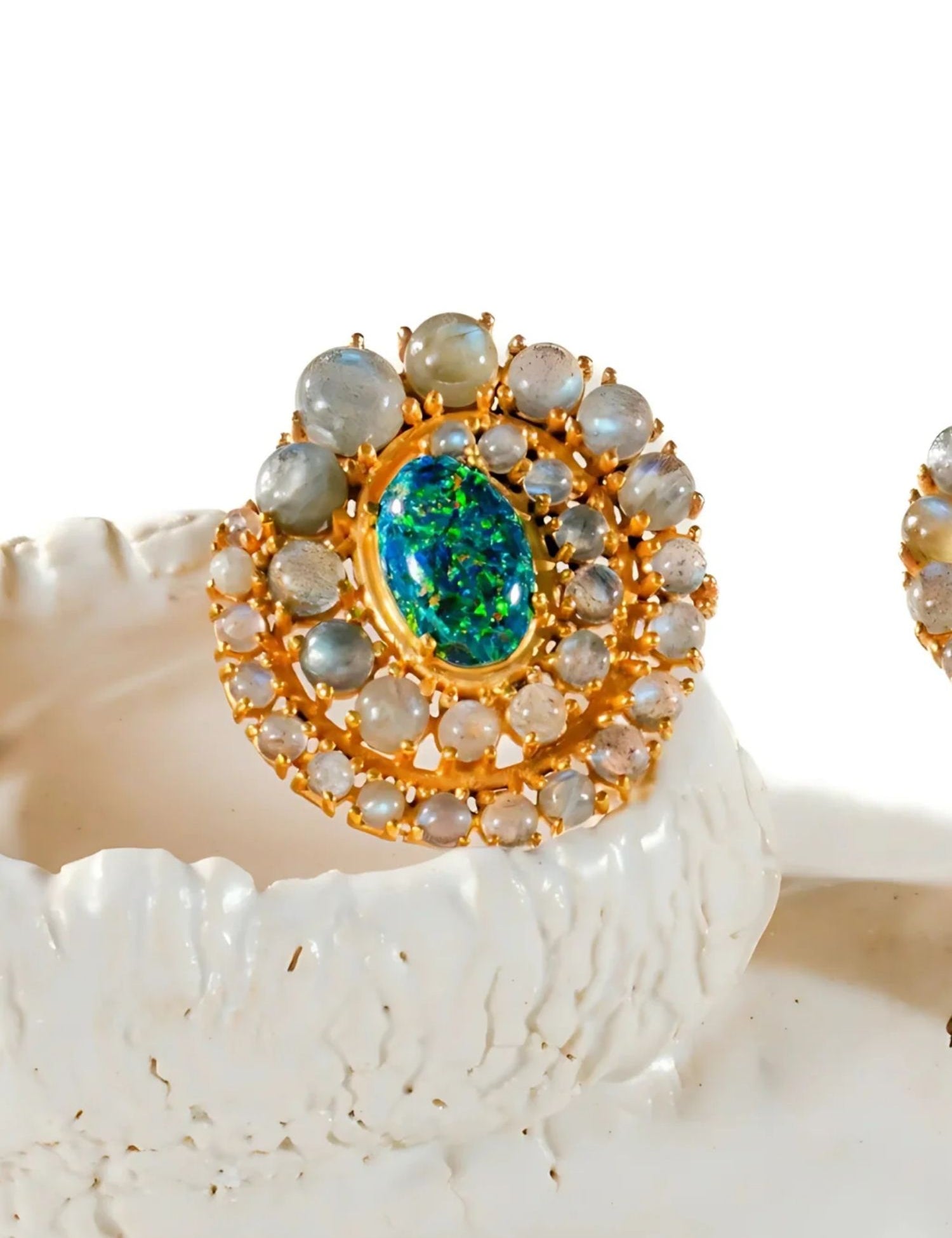 Close-up of green opal spiral earrings on white prop showing stone arrangement