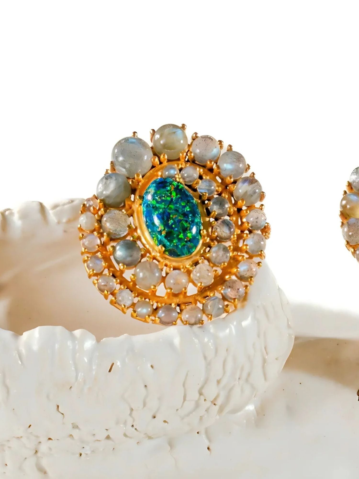 Close-up of green opal spiral earrings on white prop showing stone arrangement