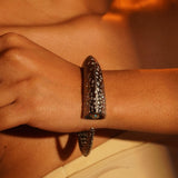 Close wrist detail of Irodori black oxidised silver statement bangle worn in warm editorial setting.