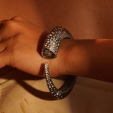 Irodori black oxidised silver bangle with zircon tip worn on wrist in warm close editorial shot.