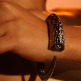 Irodori black bangle on wrist with hands crossed in warm orange editorial light.