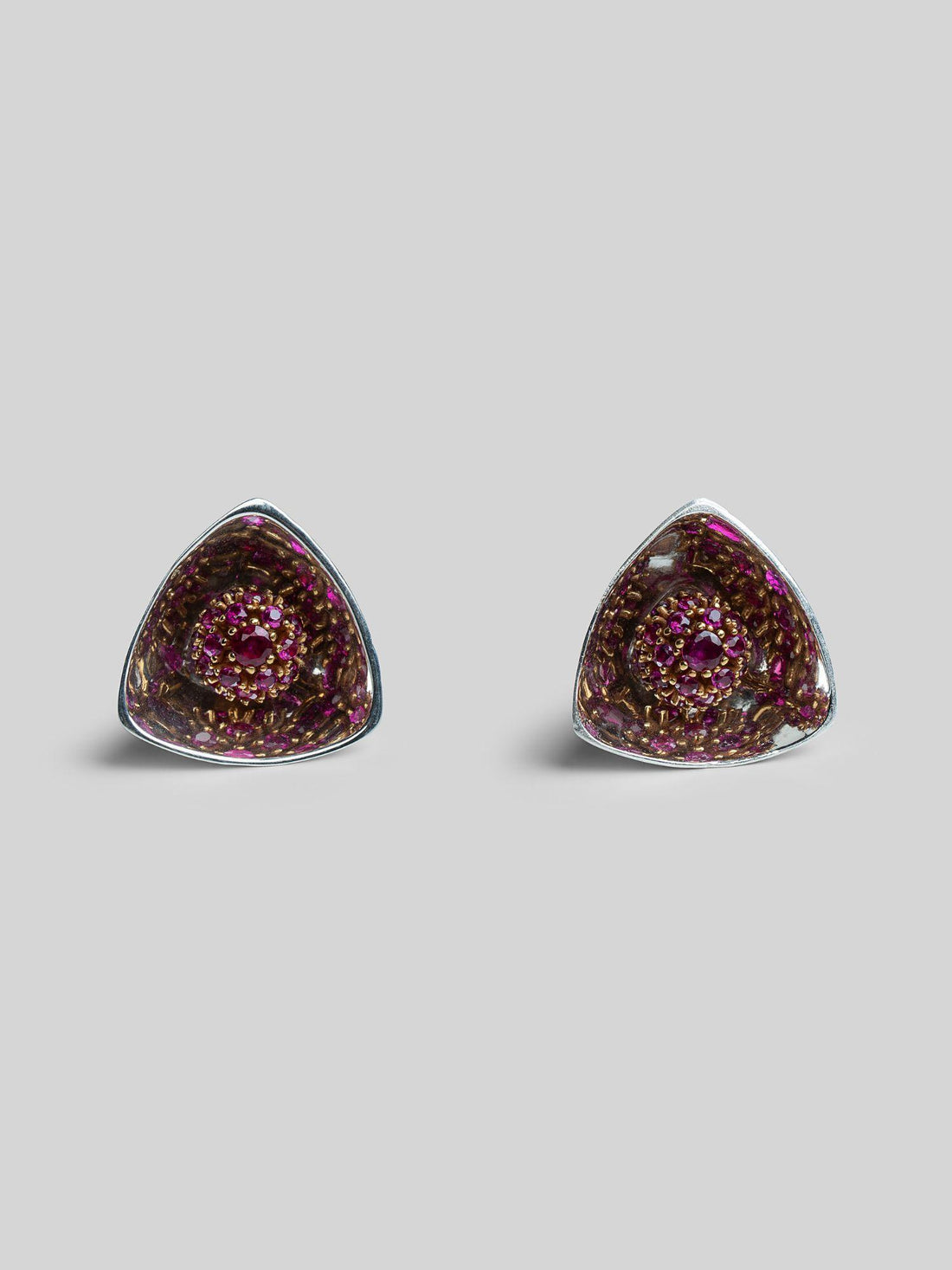 Irodori medium triangular stud earrings with pink ruby zircon cluster in silver on neutral background.