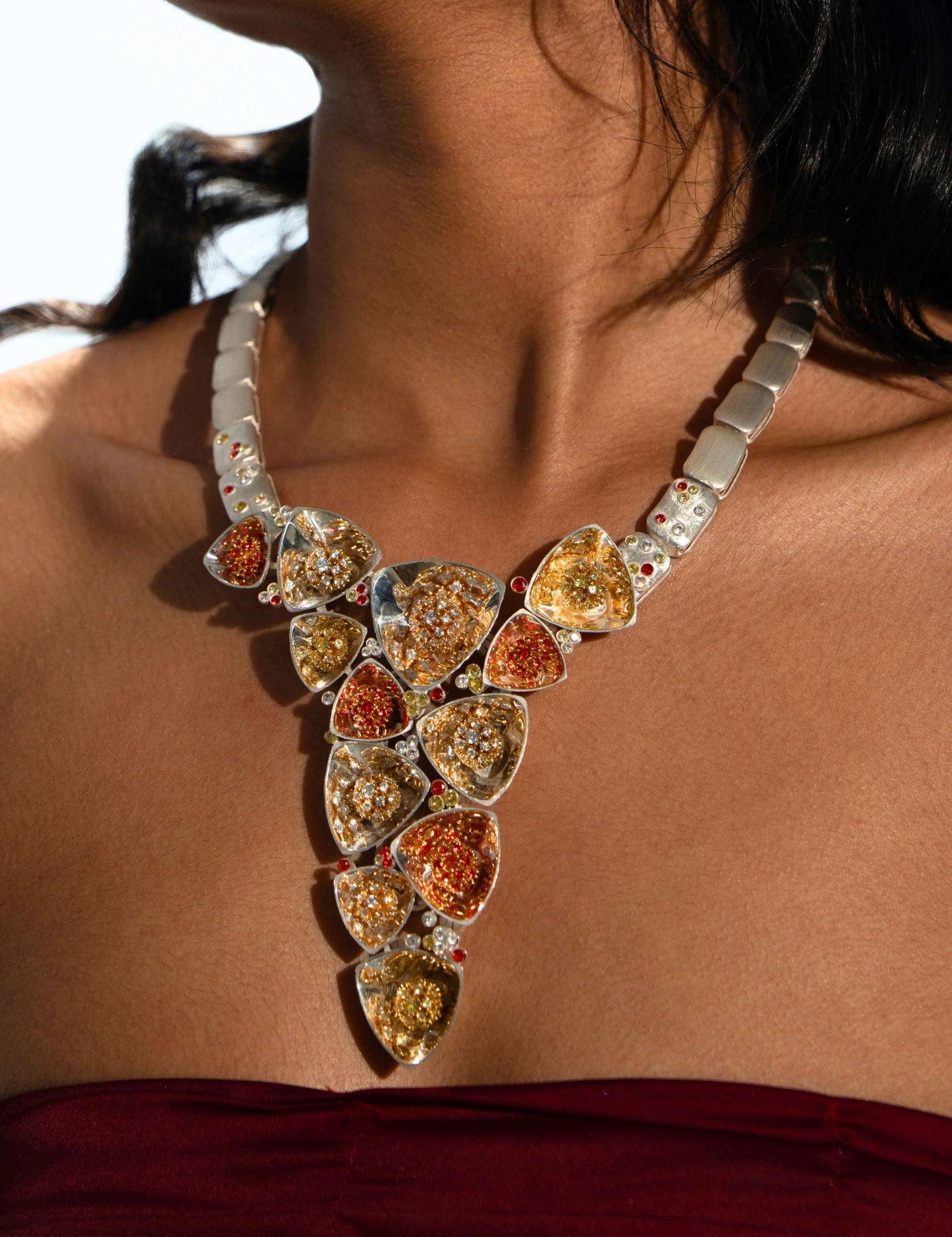 Irodori long necklace with zircon cluster pendants worn on model's décolletage in warm editorial light.