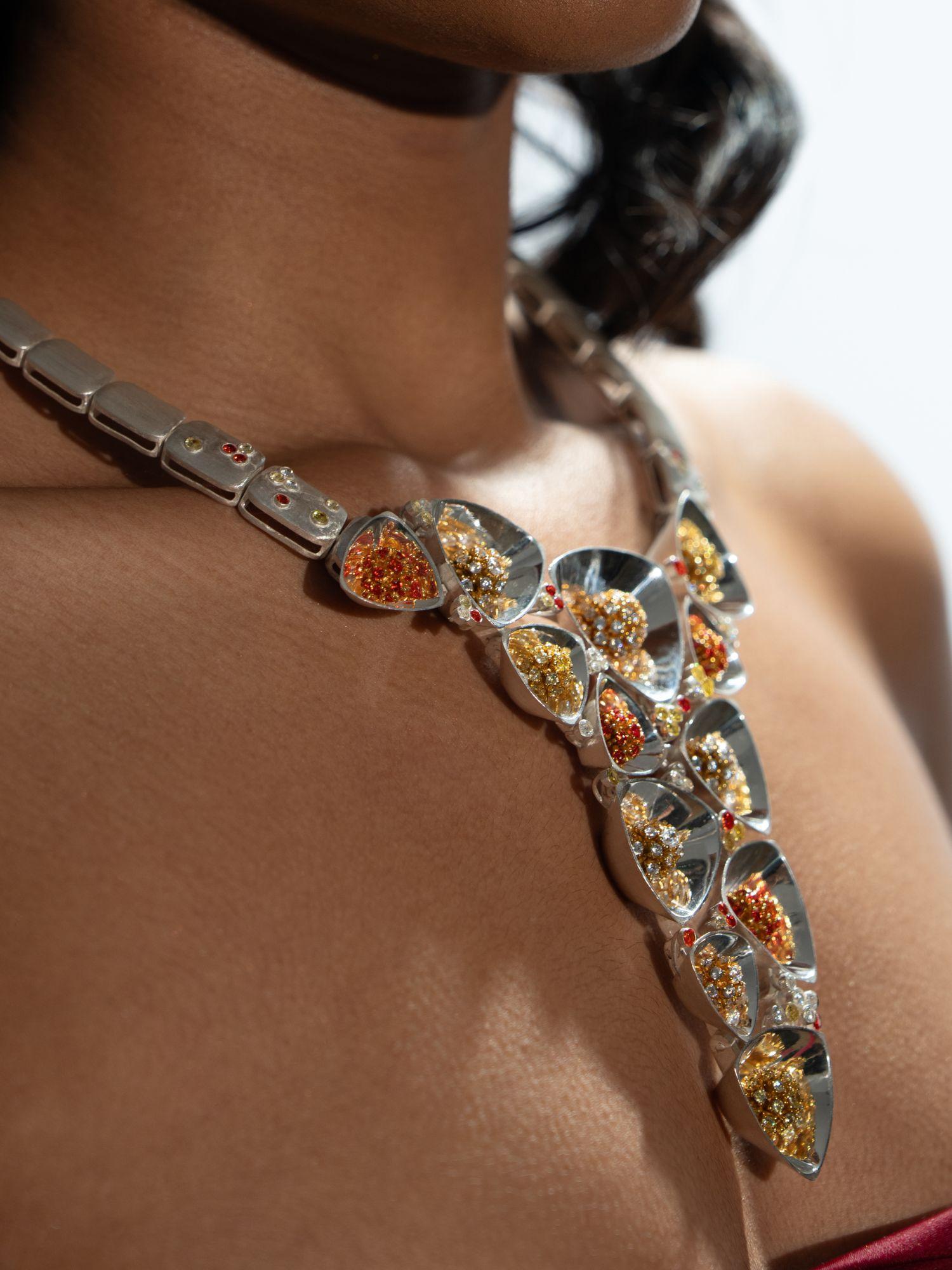 Side close-up of Irodori silver statement necklace with amber zircon clusters worn on model's neck.