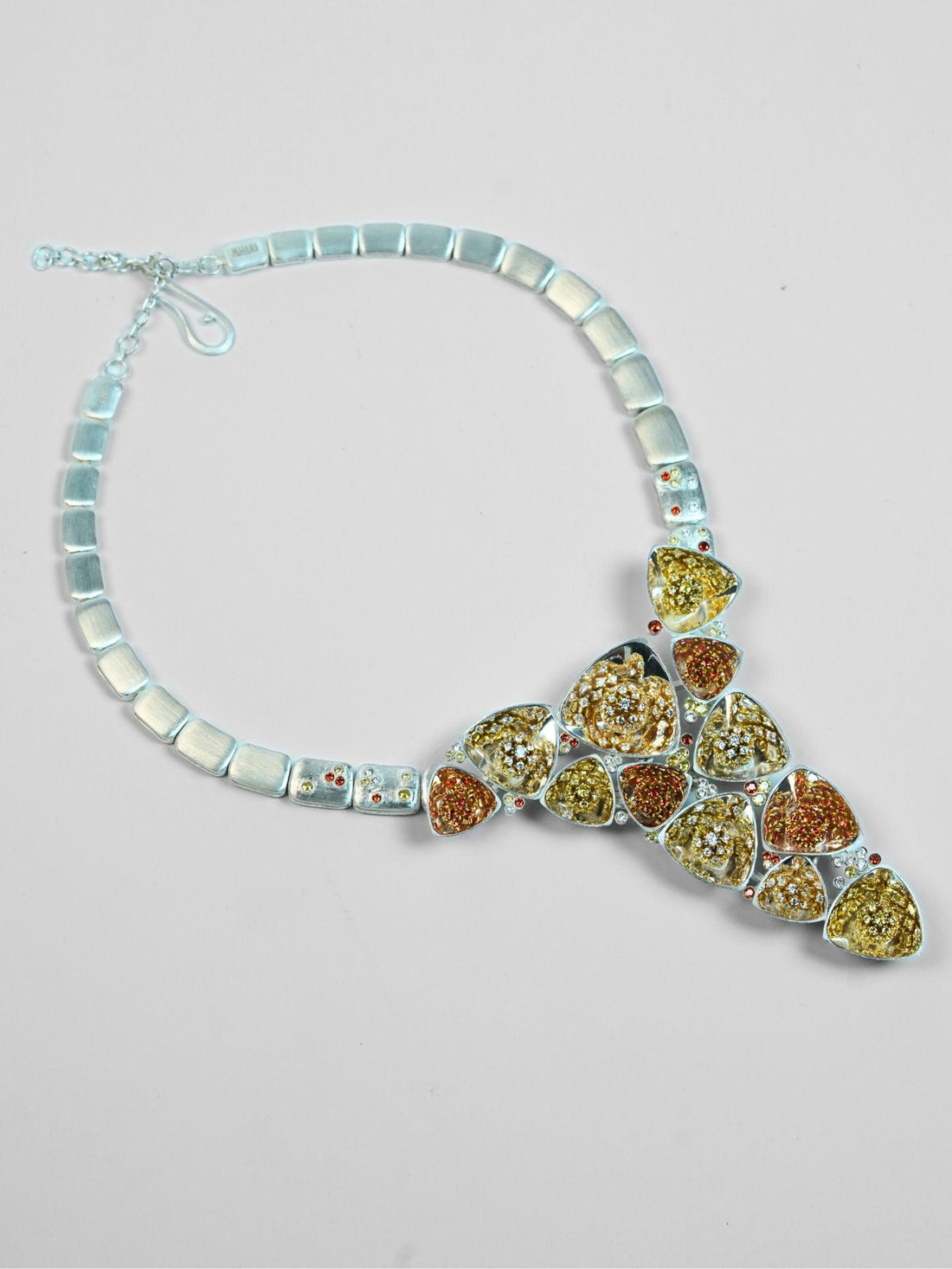 Irodori long statement necklace with mixed zircon cluster pendants in silver on neutral background.