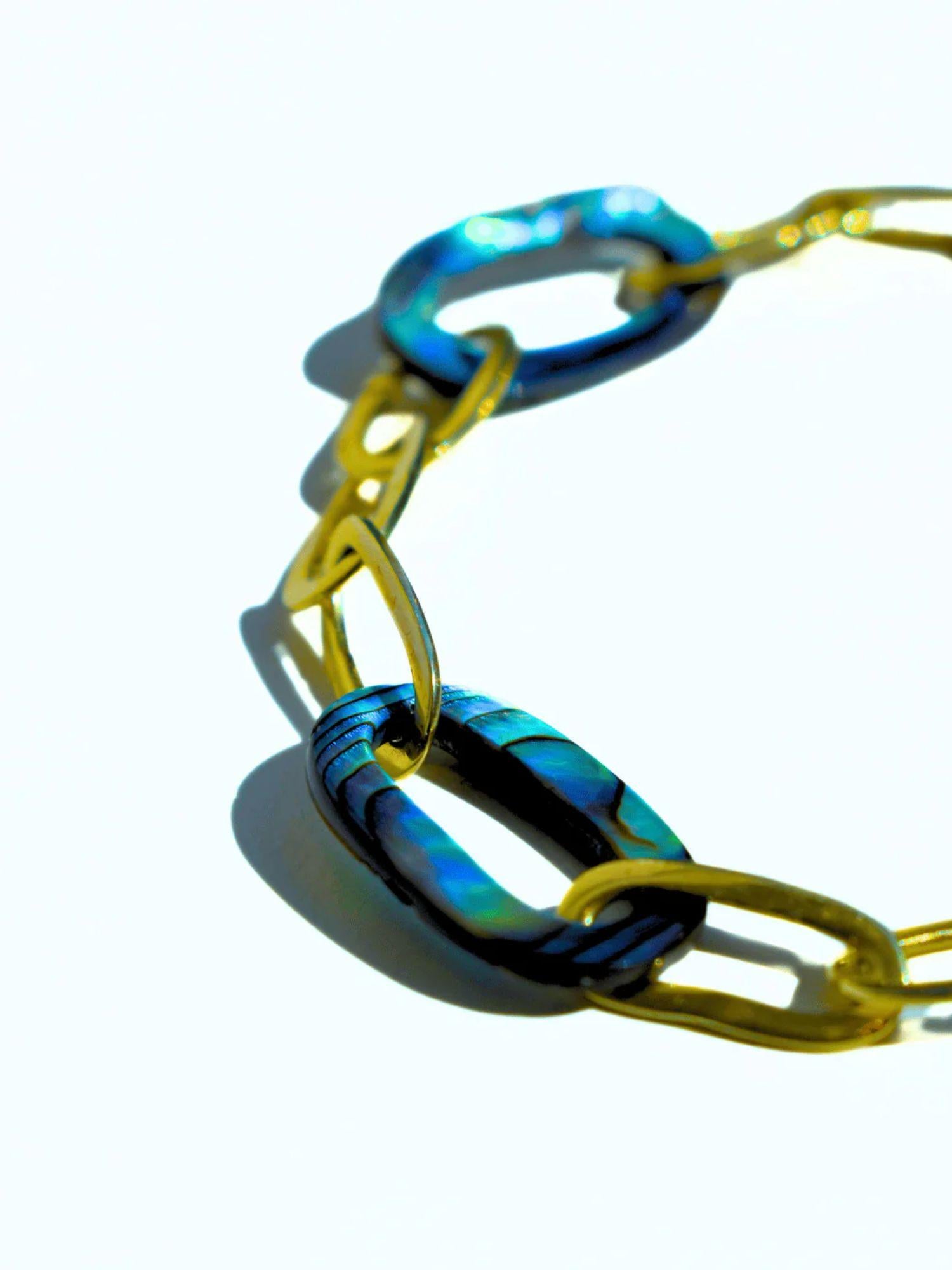 Angled product shot of bold abalone and gold oval link chain bracelet
