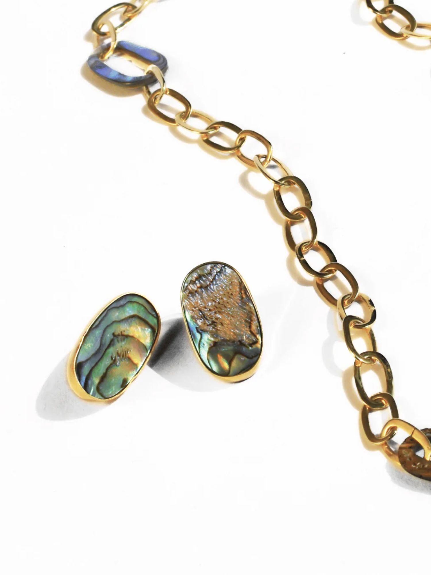 Natural abalone earrings styled next to gold link chain on white background