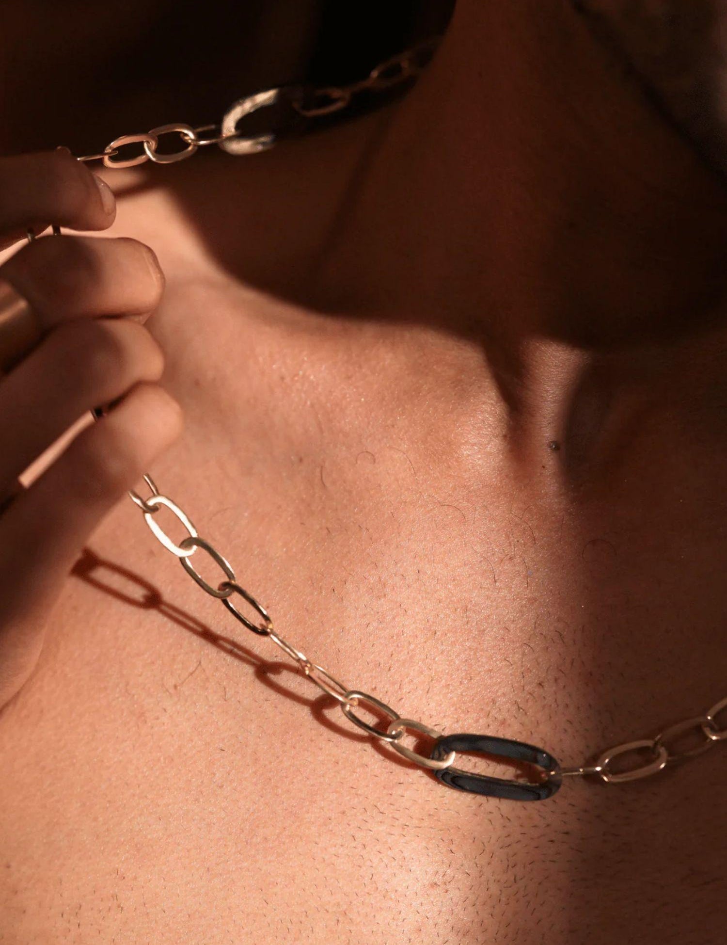 Model wearing gold abalone link chain necklace, collarbone shot in warm tones