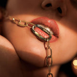 Model wearing gold abalone link chain necklace draped near mouth, close-up