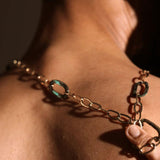 Gold abalone link chain worn on wrist as bracelet in warm dramatic lighting
