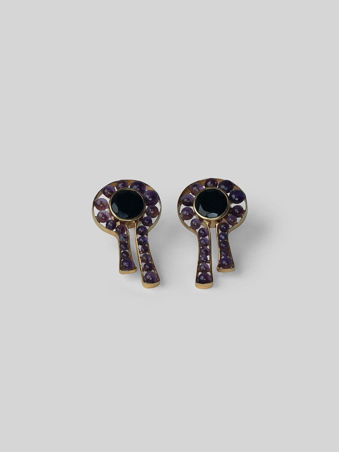 Kōmon keyhole stud earrings with black spinel centre and amethyst border in gold on neutral background.