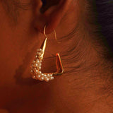 Maré gold hanger earring with natural pearl bead cluster worn in warm profile editorial shot on model.
