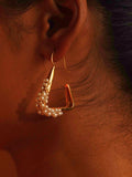 Maré gold hanger earring with natural pearl bead cluster worn in warm profile editorial shot on model.